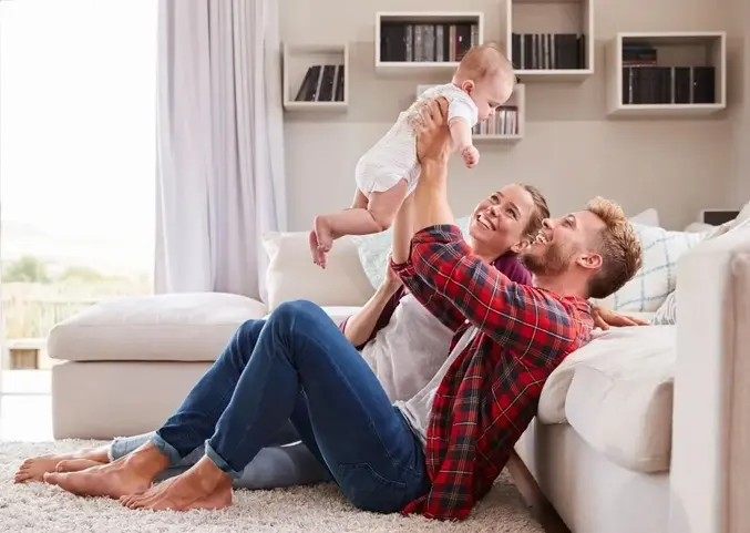 A man and woman holding a baby in the air.